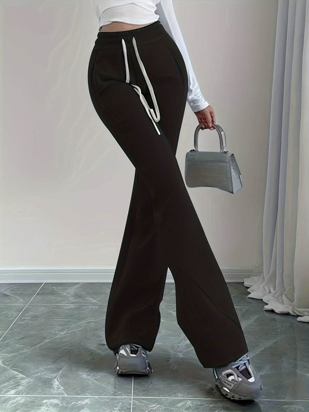 Women's black flared lounge pants paired with sneakers and a handbag